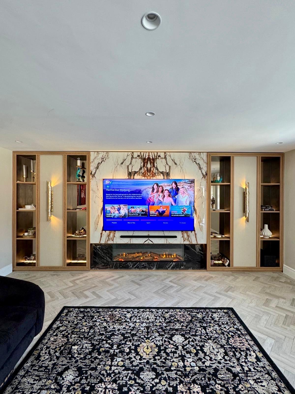 Bespoke media wall in Solihull with book-matched marble television surround, inset fireplace and oak display cabinetry with integrated lighting