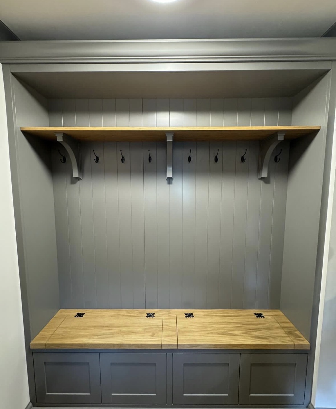 Bespoke boot room joinery with oak lift-up bench seating, cast iron hooks and shaker storage drawers