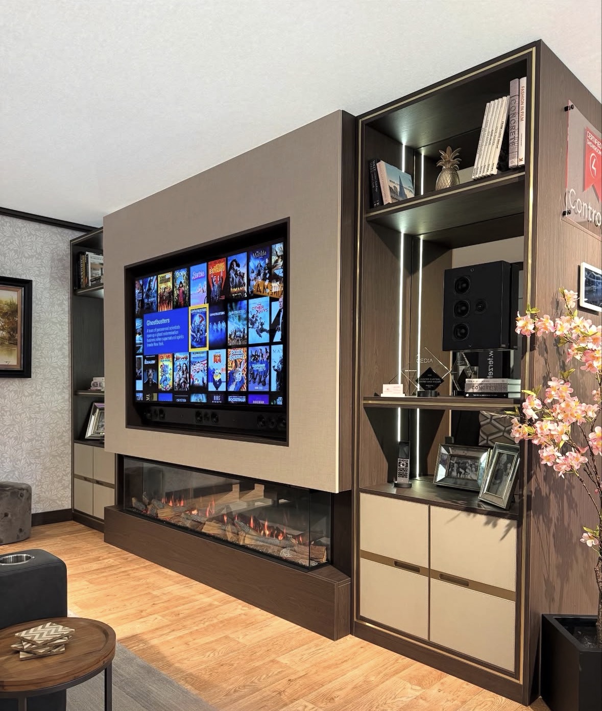 Bespoke media wall with fabric-panelled television recess, inset linear fireplace and lit walnut display shelving